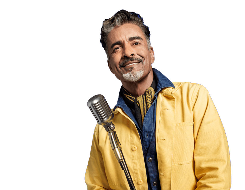 Potential KRAZATI® patient, standing with a microphone, dressed in a yellow and blue jacket against a blue background.