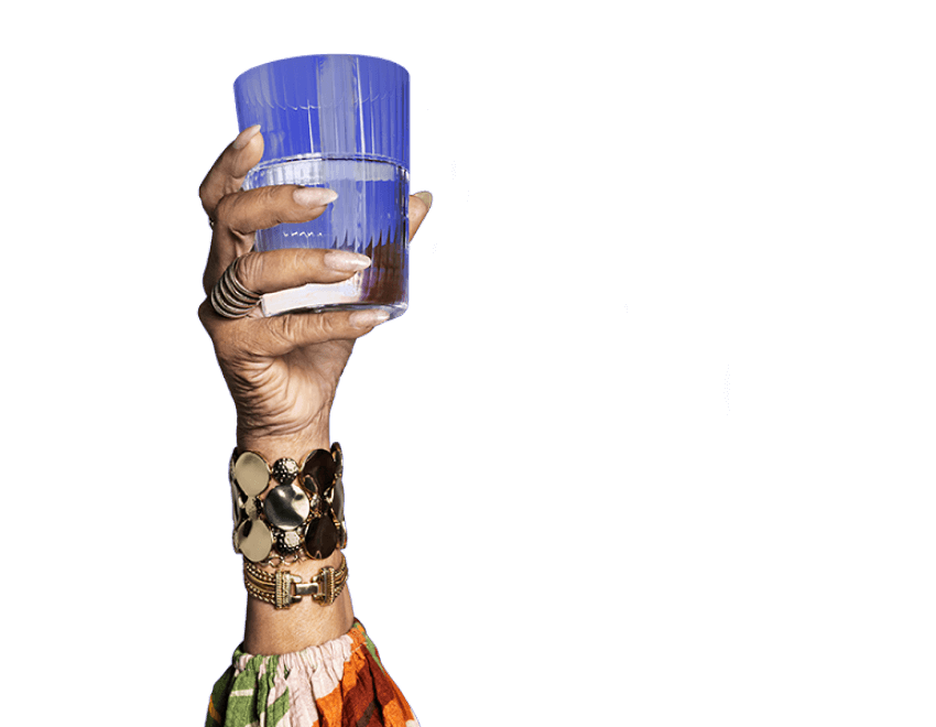 A potential KRAZATI® NSCLC patient dressed in a patterned cardigan, holding a glass of water against a blue background.